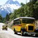 Two antique buses driving down a narrow mountain road on a sunny day